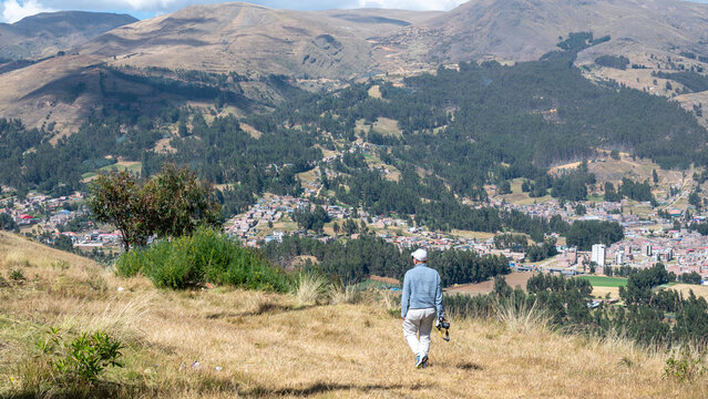 Huancayo, Peru (Per&uacute;) : A photographer walks down a dry Andean hillside overlooking the outskirts of Huancayo. Carrying a camera in his right hand, the man descends through high-altitude grassland.
