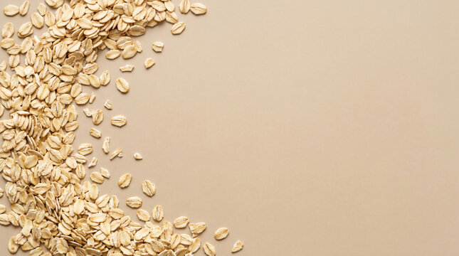 Rolled oats scattered on a beige surface, forming a curved pattern with empty space in the center.