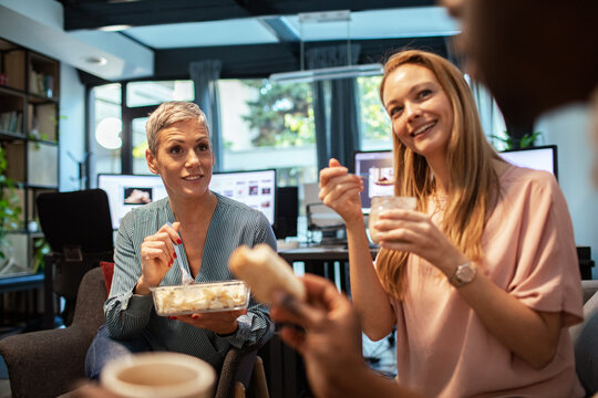 Coworkers chatting and eating lunch in a modern office