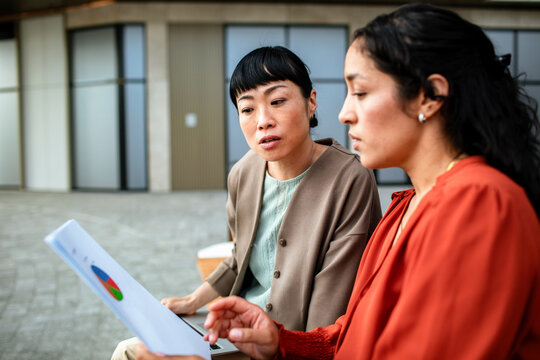 Two coworkers discuss a pie chart in the office