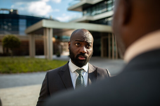 Businessman in suit listening during serious conversation outside office