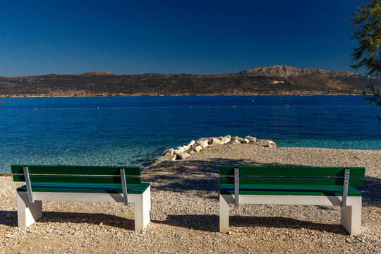 Two green benches on Slatine Beach with panoramic view of Ka&scaron;tela and mountains, Croatia
