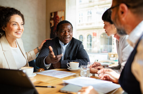 Businessman leading discussion with colleagues at a cafe