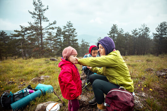 Parent zips child's jacket during mountain hike