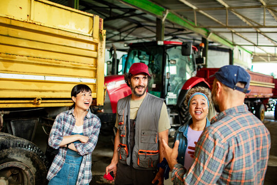 Farm team talking beside a tractor and truck in barn