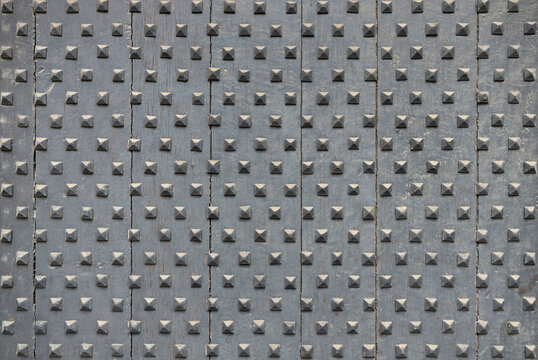 Closeup of medieval style studded wooden door spikes texture in Europe