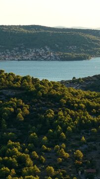 Croatia, scenic landscape of green hills, forests, and a coastal village along the blue sea
