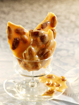 Almond brittle candy pieces in a small glass pedestal dish
