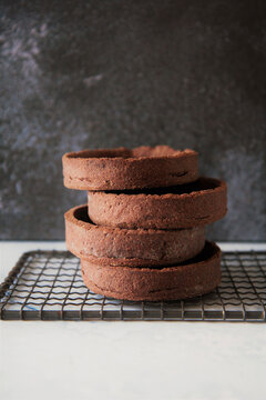 Stack of chocolate shortcrust pastry Tartelettes on cooling rack