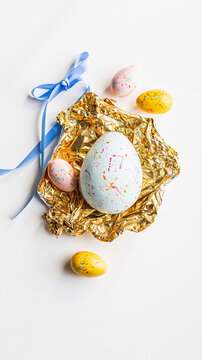 Chocolate Easter eggs in pastel colors with gold foil and blue ribbon