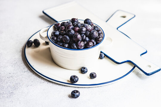 Blueberries in white bowl with round plate and cutting board