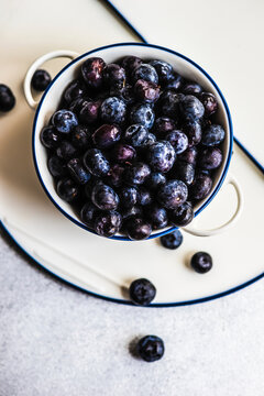 Organic blueberries in white bowl on minimalistic concrete background