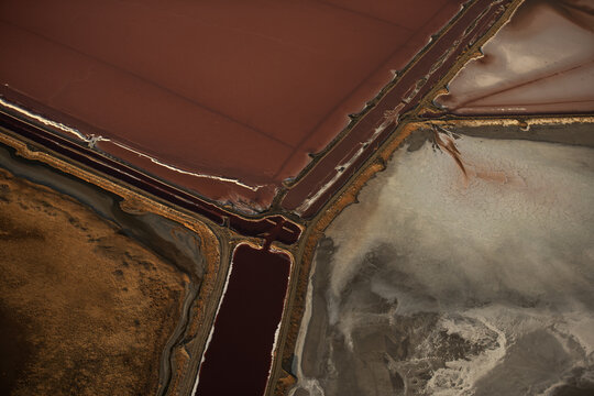 Aerial view of Great Salt Lake showing vibrant red and brown mineral-rich water separated by earthen dikes and white salt crusts in Salt Lake City, Utah, United States.