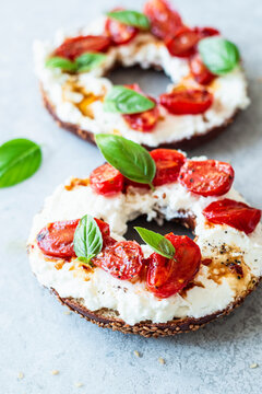 Breakfast bagel with feta cheese spread, stewed cherry tomatoes