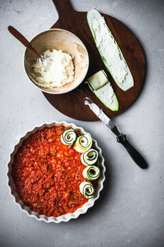 Preparing courgette rolls with ricotta, lemon and tomato sauce