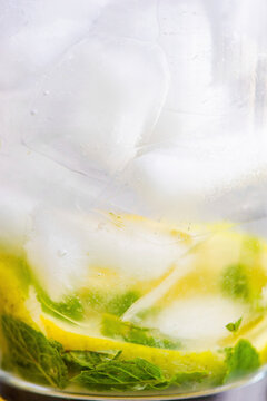 Lemon water with ice cubes and mint leaves in glass
