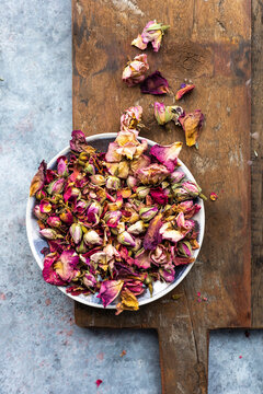Dried Edible rose petals in a bowl on wooden board