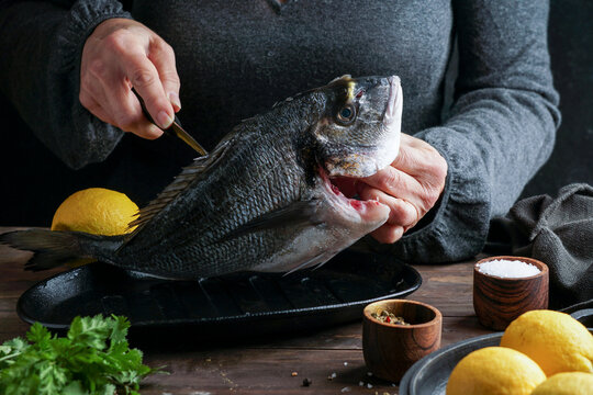 Sea bream filleted by female chef with fresh lemons and spices