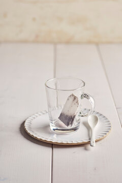Fruit tea bag in glass mug on white plate with spoon