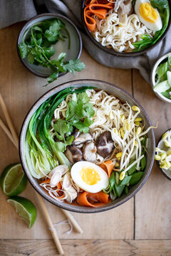 Ramen noodle bowls with vegetables and halved egg overhead view