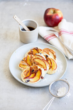 Apple pancakes with golden raisins and powdered sugar on white plate
