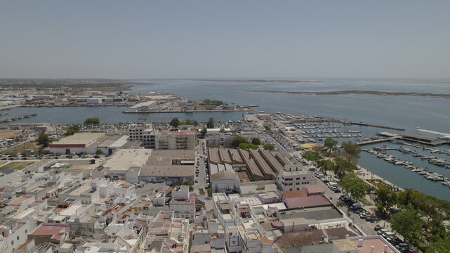Aerial view of the coastal town of Olhao, featuring the marina, fishing boats, white buildings, and the surrounding Ria Formosa lagoon in Olhao, Faro District, Portugal.