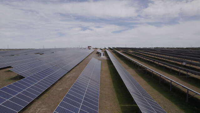 Aerial view of a large solar farm with rows of photovoltaic panels installed in an open field under a cloudy sky in Ourique, Beja District, Portugal.