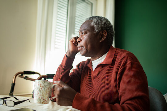 Senior man holding mug and gazing out the window