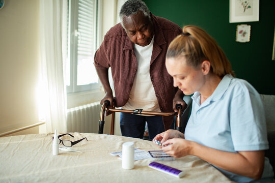 Caregiver organizing medication for senior man at home