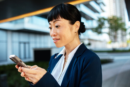 Businesswoman texting on smartphone outside office