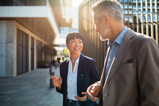 Business colleagues walking and talking outside office buildings