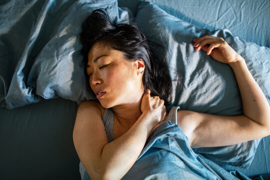 Woman in bed massaging a painful neck