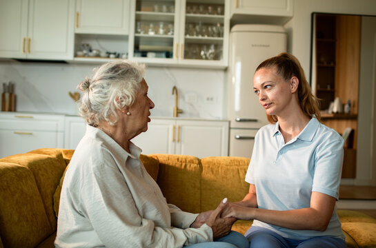 Caregiver holding hands with senior woman at home
