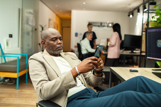 Man with feet up using smartphone in office