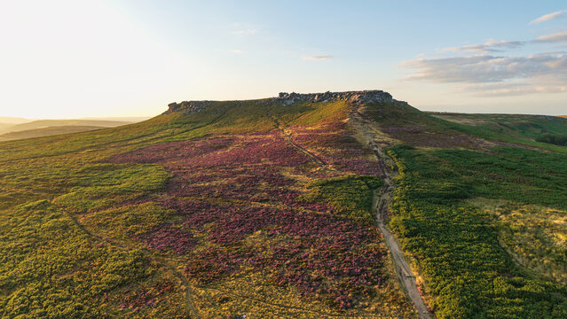 Beautiful drone landscape image view over Burbage South Edge in Peak District during Summer heather sunset