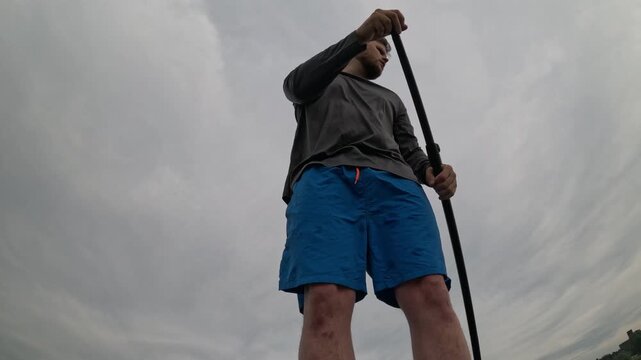 Man paddling SUP on cloudy lake