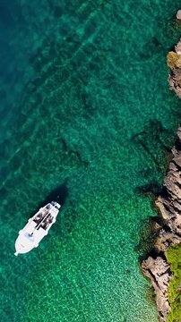 Croatia, aerial view of a boat floating on crystal clear turquoise sea water near rocky coast