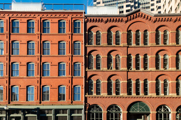 Classic red-brick facades in downtown Boston, Massachusetts, United States, display rows of arched windows, decorative masonry and stone trim below modern glass buildings. © Jose Luis Stephens