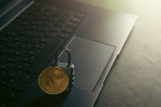 Golden Bitcoin with padlock on laptop computer background. Cryptocurrency concept.