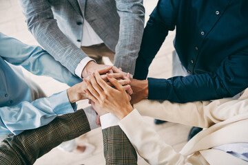 Obraz na płótnie Canvas Professional colleagues stacking hands in a meeting, showcasing teamwork and collaboration in a formal business office environment