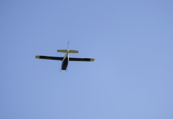 A view from below of a small blue propeller airplane flying alone against a clear blue sky © GezerFreitas