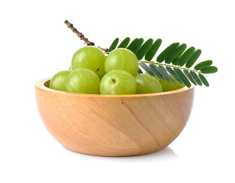 Wooden bowl of  amla fruit with green leaf on white background