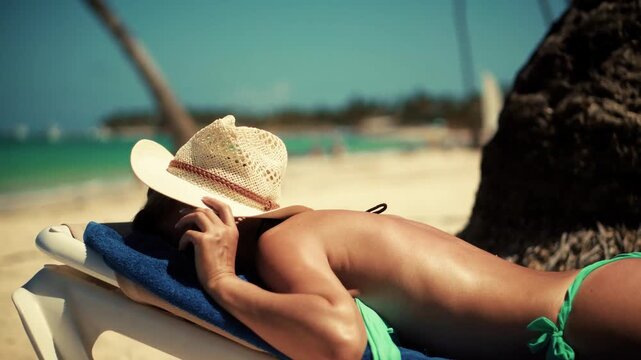 Sunbather Resting On Lounge Chair By Turquoise Sea During Summer Beach Vacation