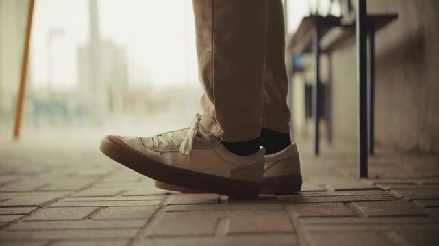 Person Standing On Brick Sidewalk Wearing Casual Sneakers And Pants In Urban Setting