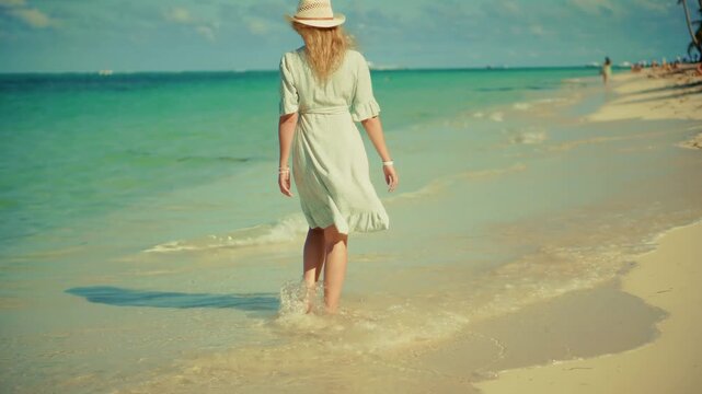 Vacationer Walking Barefoot Along Sandy Beach With Turquoise Ocean