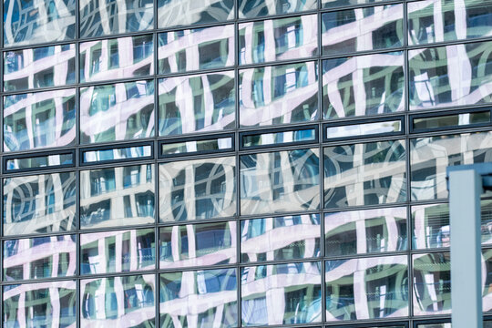 Abstract glass facade with distorted reflections forming a geometric grid across modern architecture in soft light from a close exterior view