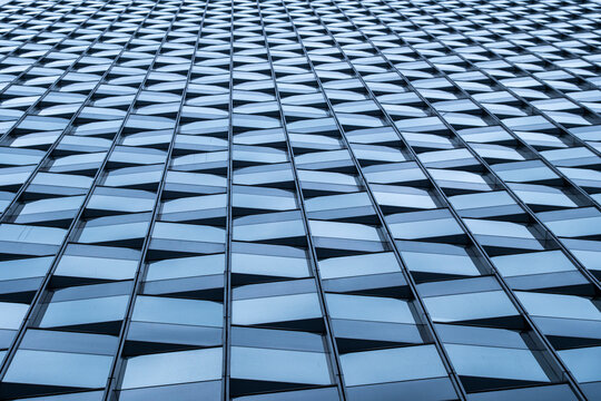 Glass facade with a geometric grid creating repeated architecture across a modern building exterior from a low perspective in daylight