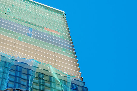 Modern glass building with a reflective facade and layered architecture rising against a clear blue sky from a dramatic low angle perspective