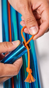 Hands threading elastic shock cord through hollow anodized aluminum tent pole close up