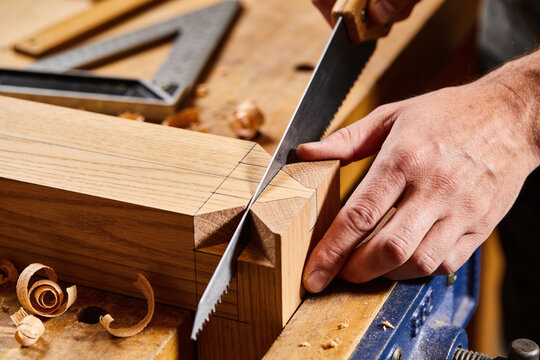 Hands cutting a dovetail joint with a fine saw